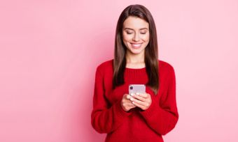 Woman looking at phone against pink background