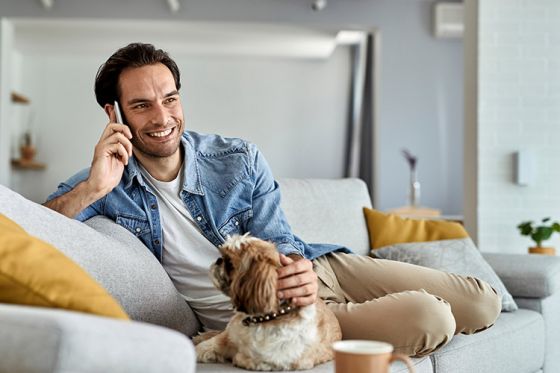 Man patting dog while making phone call
