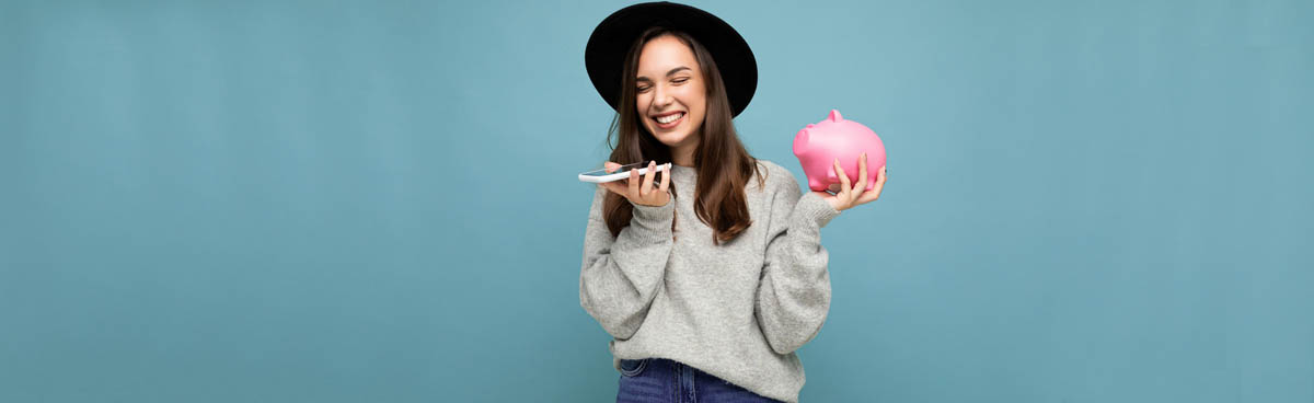 Happy young woman holding smartphone and piggy bank