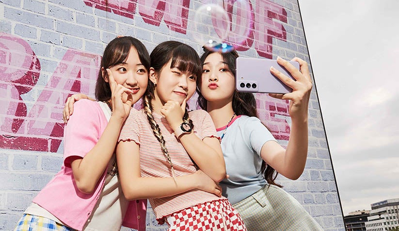 Three teen girls taking selfie with purple Samsung phone 