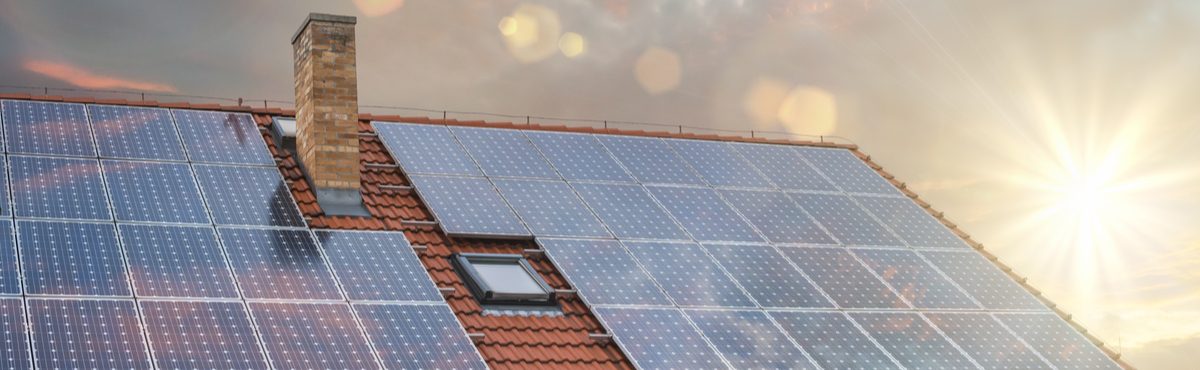 Solar panels on a roof with sun rising in the background