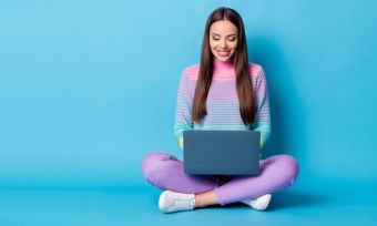 Young woman looking at laptop against blue background
