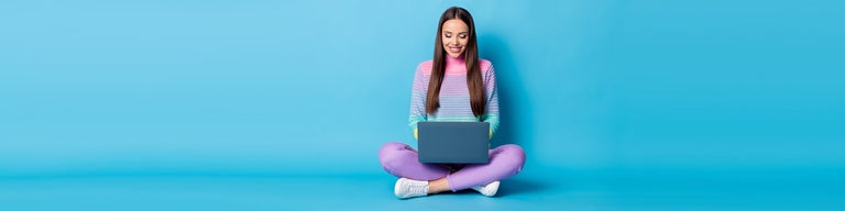Young woman looking at laptop against blue background