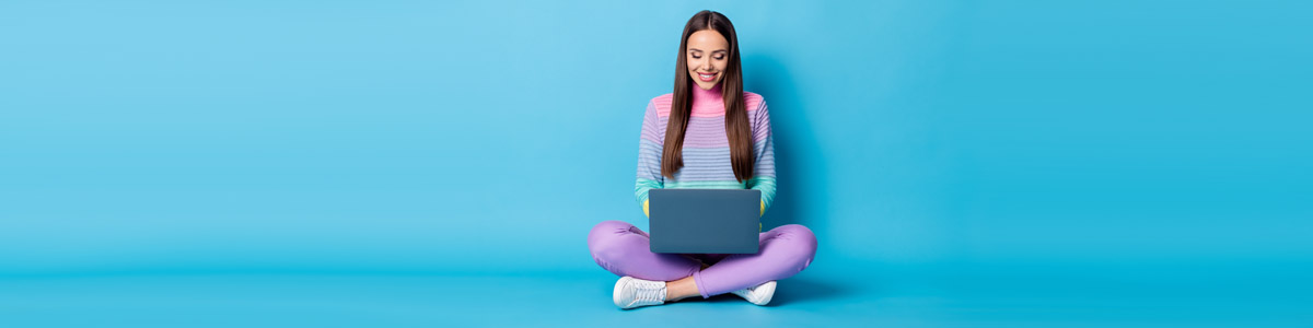 Young woman looking at laptop against blue background