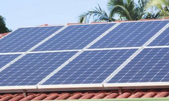 Solar panels on a rooftop with palm trees in the background