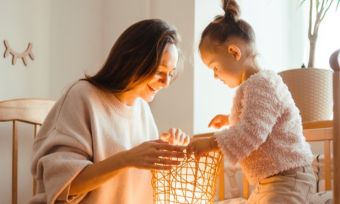 Mother and daughter looking at a lamp with a yellow glow on their faces