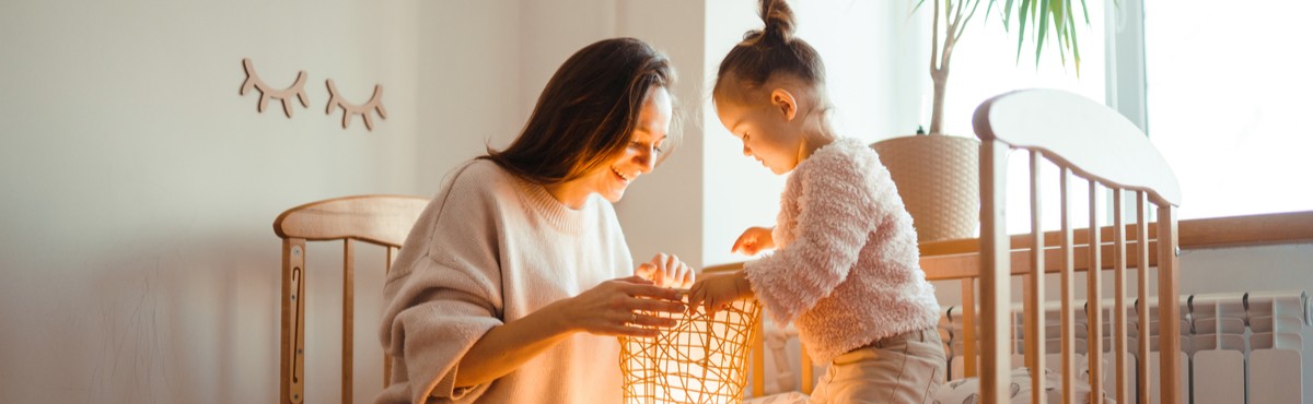 Mother and daughter looking at a lamp with a yellow glow on their faces