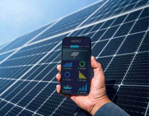 Man holding phone in front of solar panels with monitoring information displayed on it 