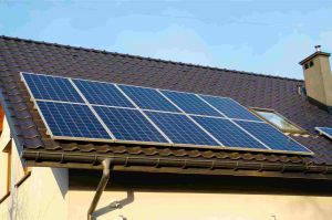 Solar panels sitting at the bottom of a roof, facing sunlight 