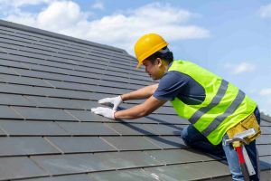 Tiler on top of roof fixing grey tiles 