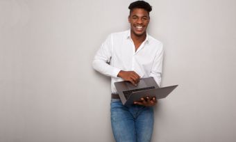 Smiling young black man holding laptop