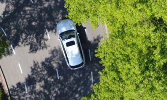 Electric vehicle driving through trees birds eye view