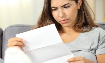 Lady sitting on couch with energy bill looking confused