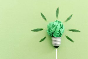 Lightbulb made out of green paper with green leaves coming off as light. 