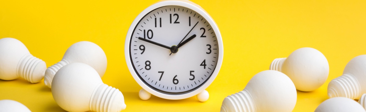 Clock on yellow background with light bulbs