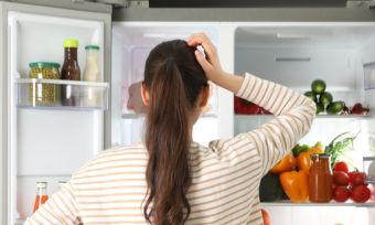 Woman staring into fridge, looking for something to eat