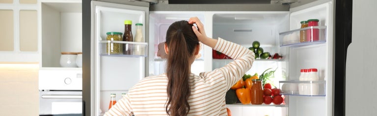 Woman staring into fridge, looking for something to eat