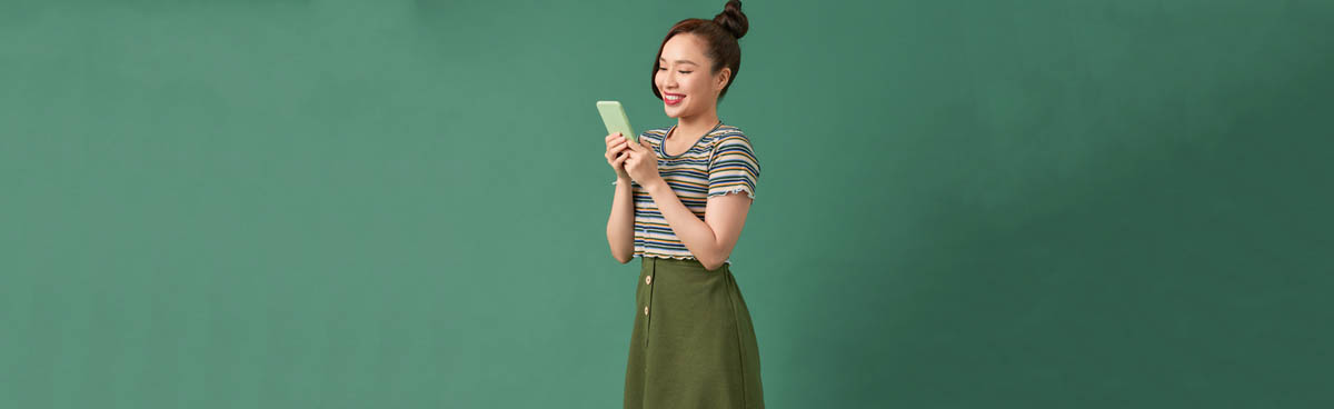 Young woman using phone with green background