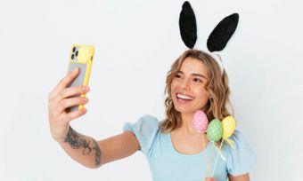 Young woman taking selfie with rabbit ears and Easter eggs
