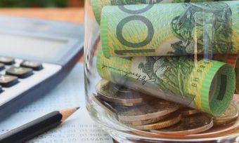 Jar with $100 notes in it next to notebook and calculator