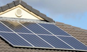 Solar panels on a rooftop with blue sky behind it.