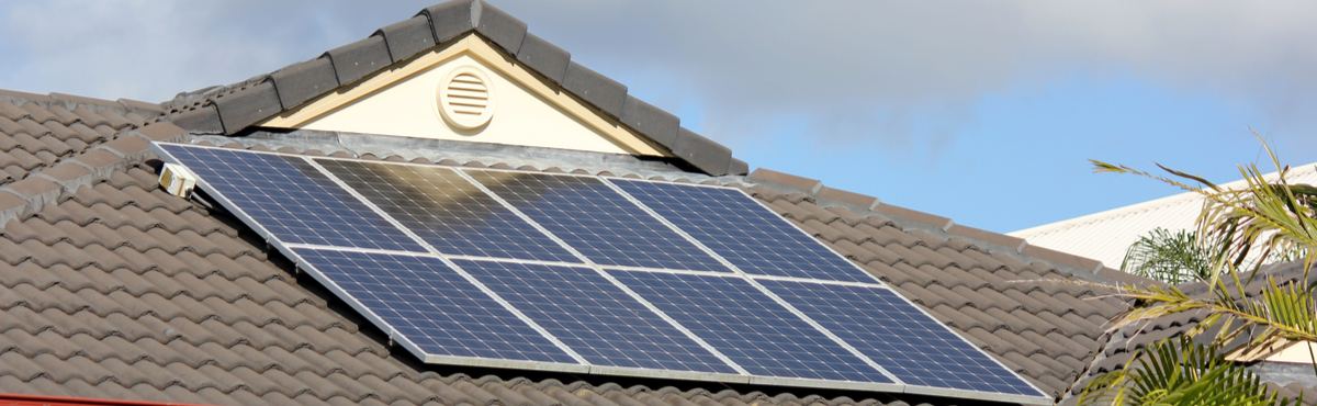 Solar panels on a rooftop with blue sky behind it.