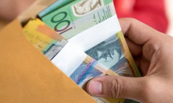 Hand pulling bundle of $100 (Australian) notes out of manila folder