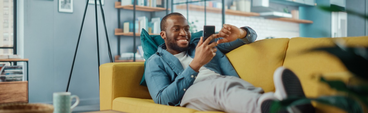 Man laying on lounge smiling at phone