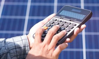 Man holding calculator in front of solar panels