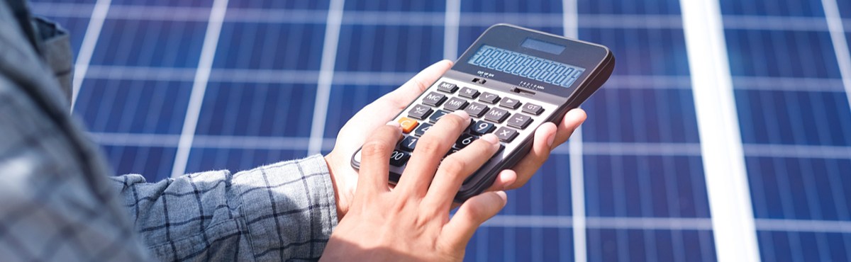 Man holding calculator in front of solar panels