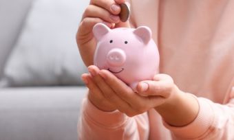 Person putting coins in a pink piggy bank