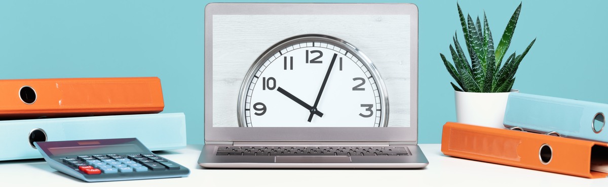 Clock on laptop screen on blue desk with decorations.