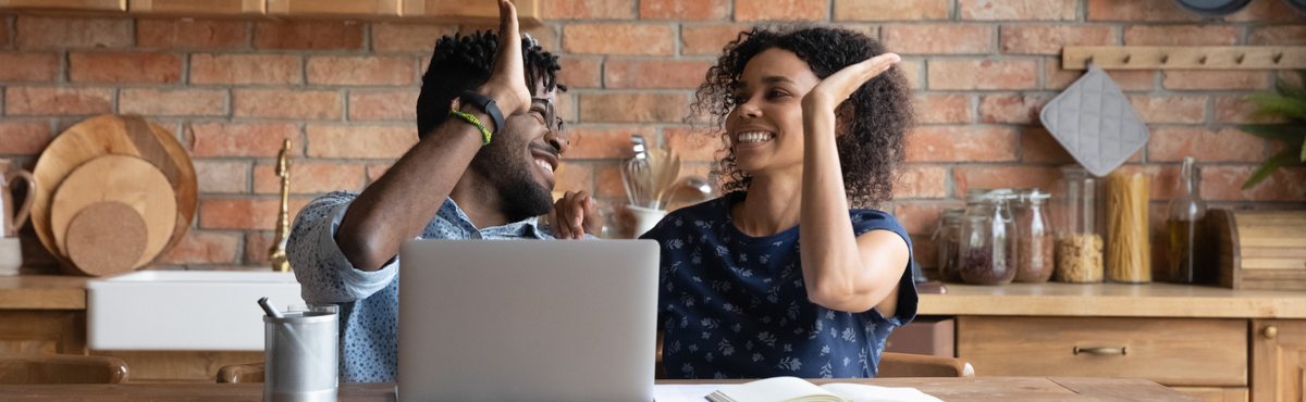 Man and woman high-fiving with laptop in front of them