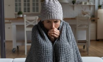 Woman sitting wrapped in blanket with beanie on