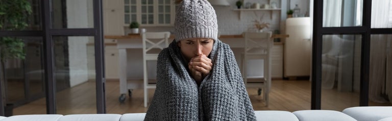 Woman sitting wrapped in blanket with beanie on