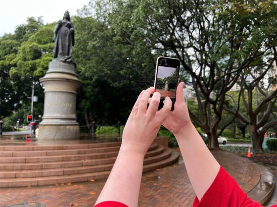 Hands using the iPhone SE 2022 to take a photo of a statue