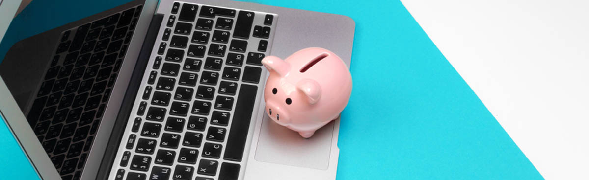 A piggy bank next to a laptop