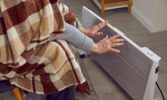 person sitting in front of heater with blanket over them