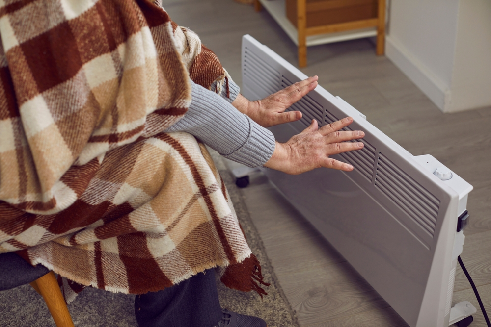 person sitting in front of heater with blanket over them