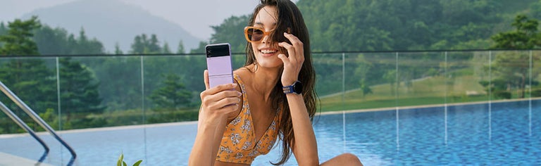 Woman by pool using purple flip phone
