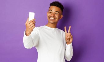 Young man taking selfie and flashing peace sign