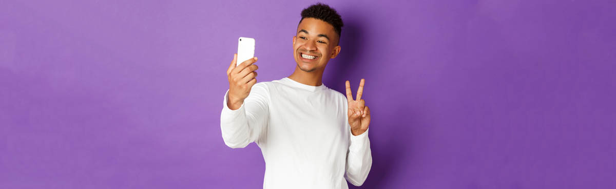 Young man taking selfie and flashing peace sign