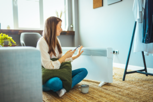 woman sitting next to panel heater