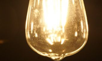 Three yellow light bulbs hanging in dark room.