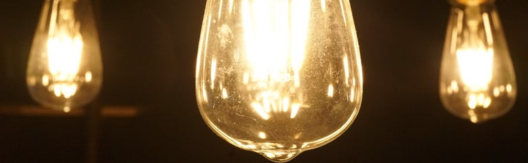 Three yellow light bulbs hanging in dark room.