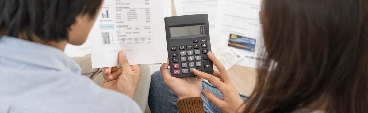 Couple looking at energy bills and working out costs with a calculator.