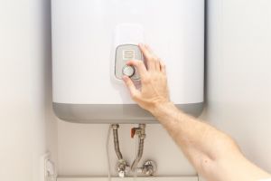 Man's hand turning on hot water system. 