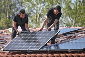 Two solar installers fixing panel to roof