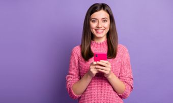 Woman holding phone in front of purple background