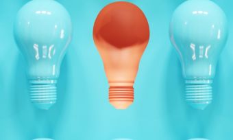 Blue light bulbs on blue background with one orange light bulb in the centre.